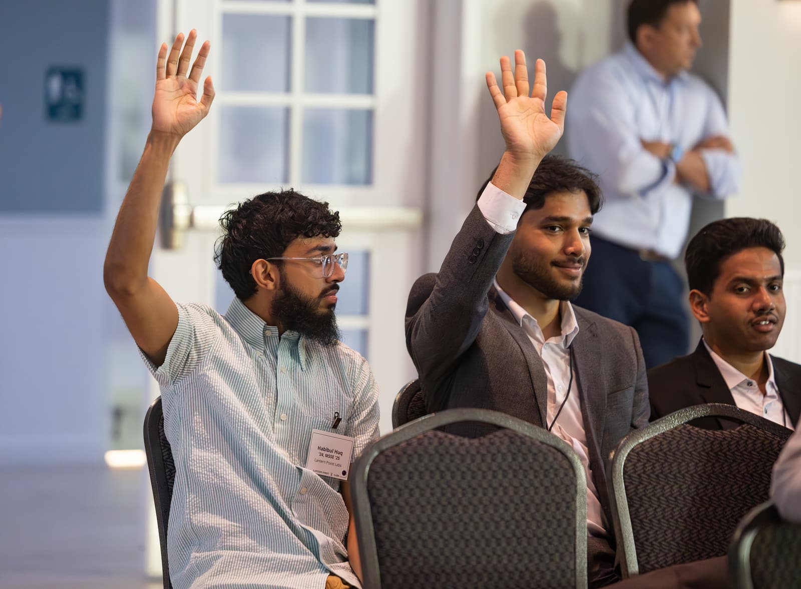 Audience members raise their hands during a session at an LPL event